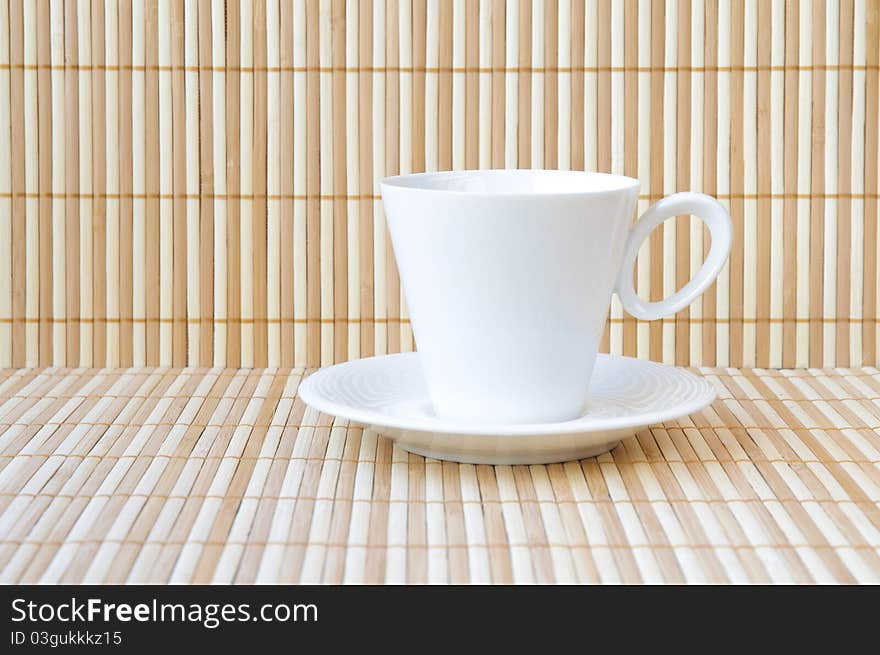 White empty cup and saucer on bamboo background