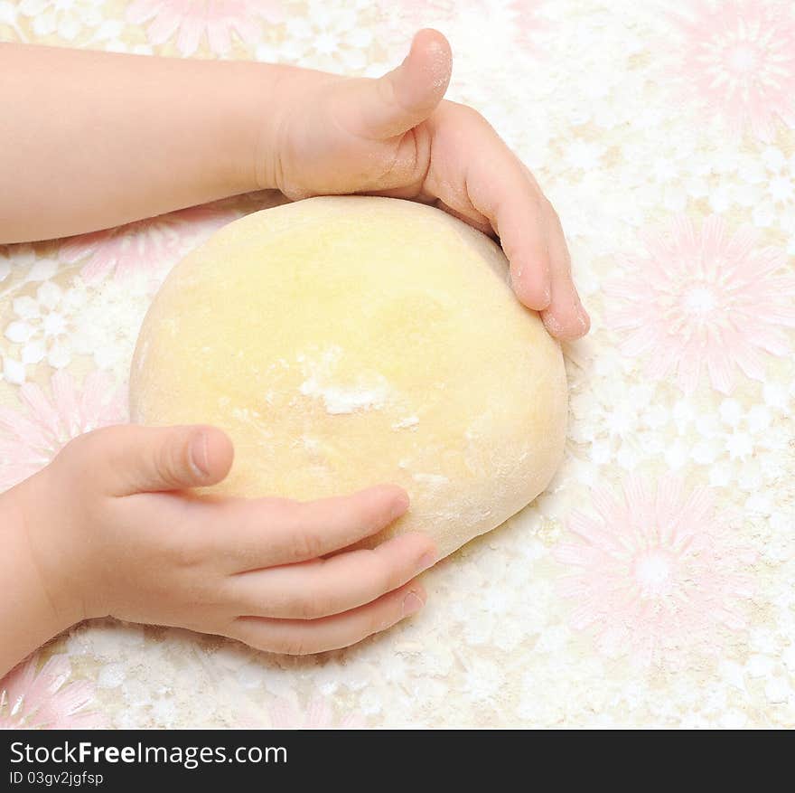 Child's hands kneading dough on table