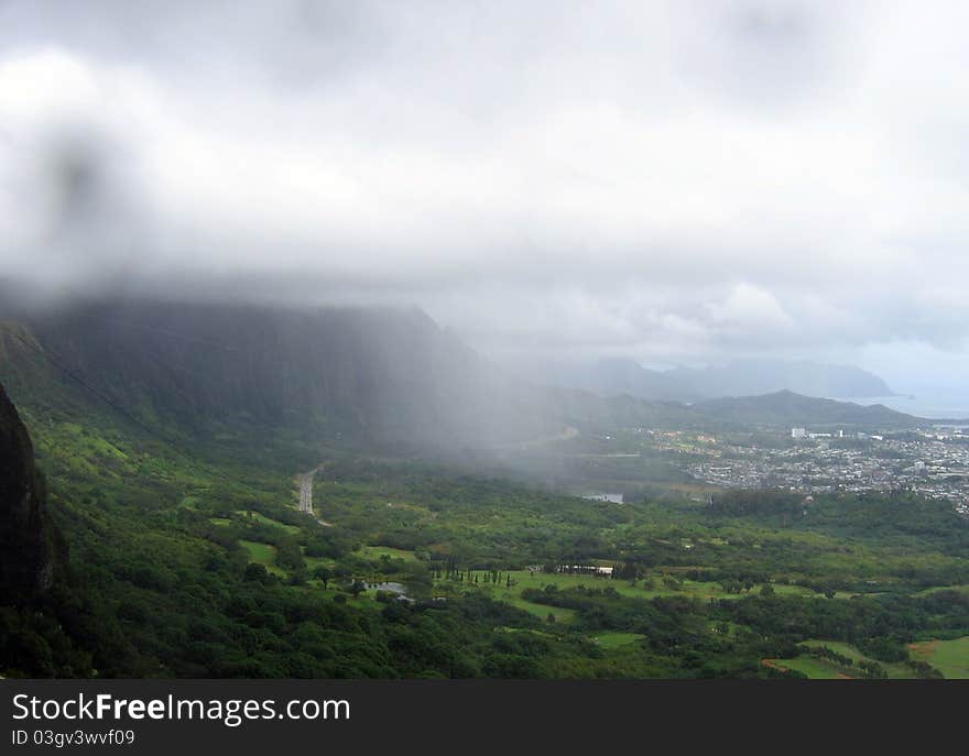 Rain falls in the valley of the Nuuanu Pali Lookout (Cool Height Cliff)overlooking the 985 foot cliffs of the Koolau Mountain Range, is one of the best views on O'ahu. It was here in 1795 that King Kamehameha and his warriors defeated the O'ahu armies by sending them over these steep, forested cliffs and claiming his victory and uniting the Hawaiian Islands. The breathtaking sight and the gruesome history of the battle fought here is enough to cause a chill to run up your spine. Add to that the incredible winds that often pass through the Pali and you may be swept off your feet!