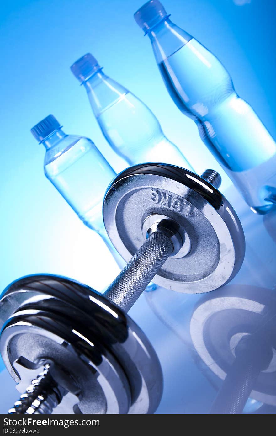 Dumbells and bottles of water on the blue background