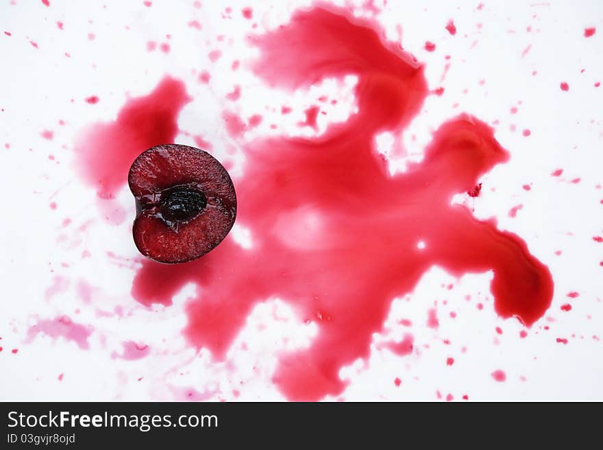 Image of fresh cherry cut in halves with  cherry juice on white