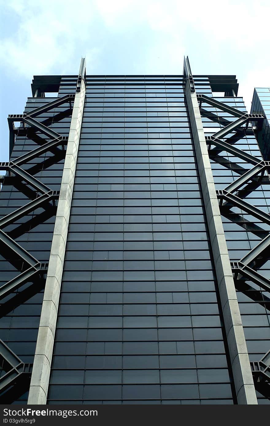 Front upward view of a high-rise glass and metal structure commercial building with stylish zigzag steel decorations on sides. Front upward view of a high-rise glass and metal structure commercial building with stylish zigzag steel decorations on sides