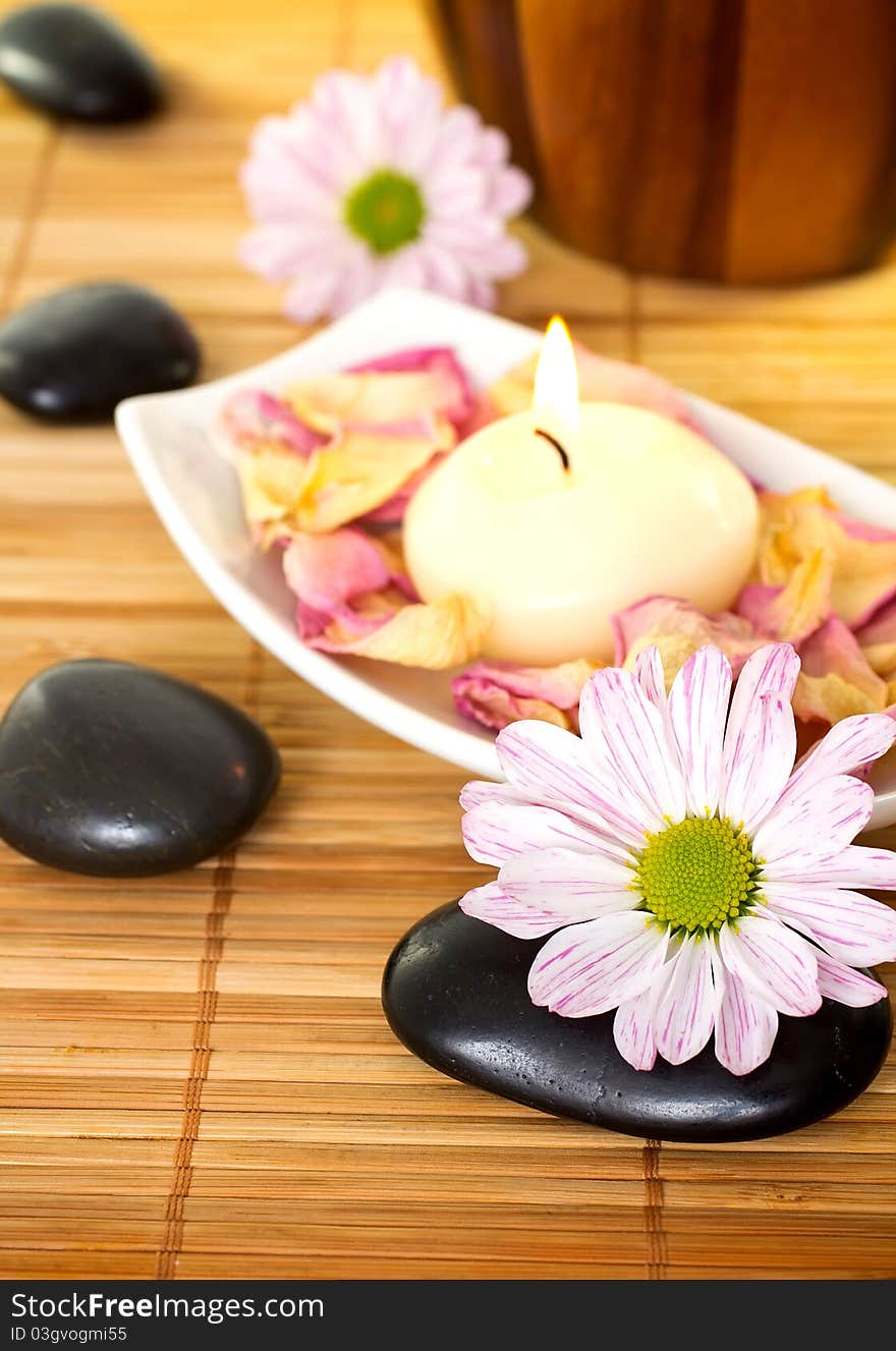 Spa treatment. Spa stones and burning candle, pink flowers.