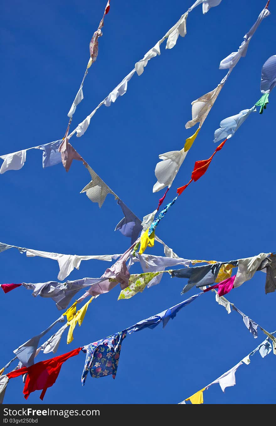 A group of colored shirts on a clothesline in front of blue sky