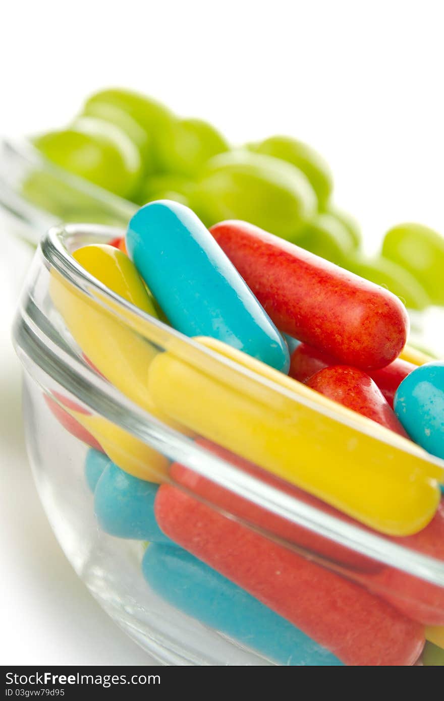 Two glass plates filled to the brim with tasty colorful candies. Isolated. Two glass plates filled to the brim with tasty colorful candies. Isolated