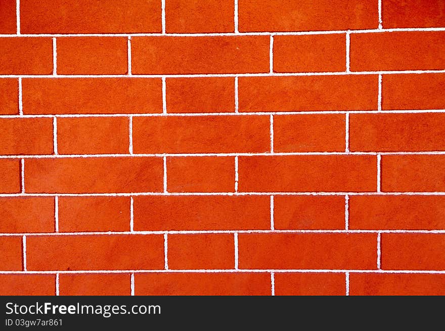 A wall built of smooth bright red brick. A wall built of smooth bright red brick