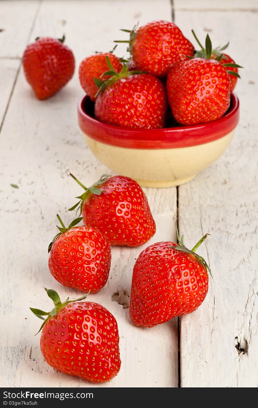 Strawberries in a small dish on a wooden painted table