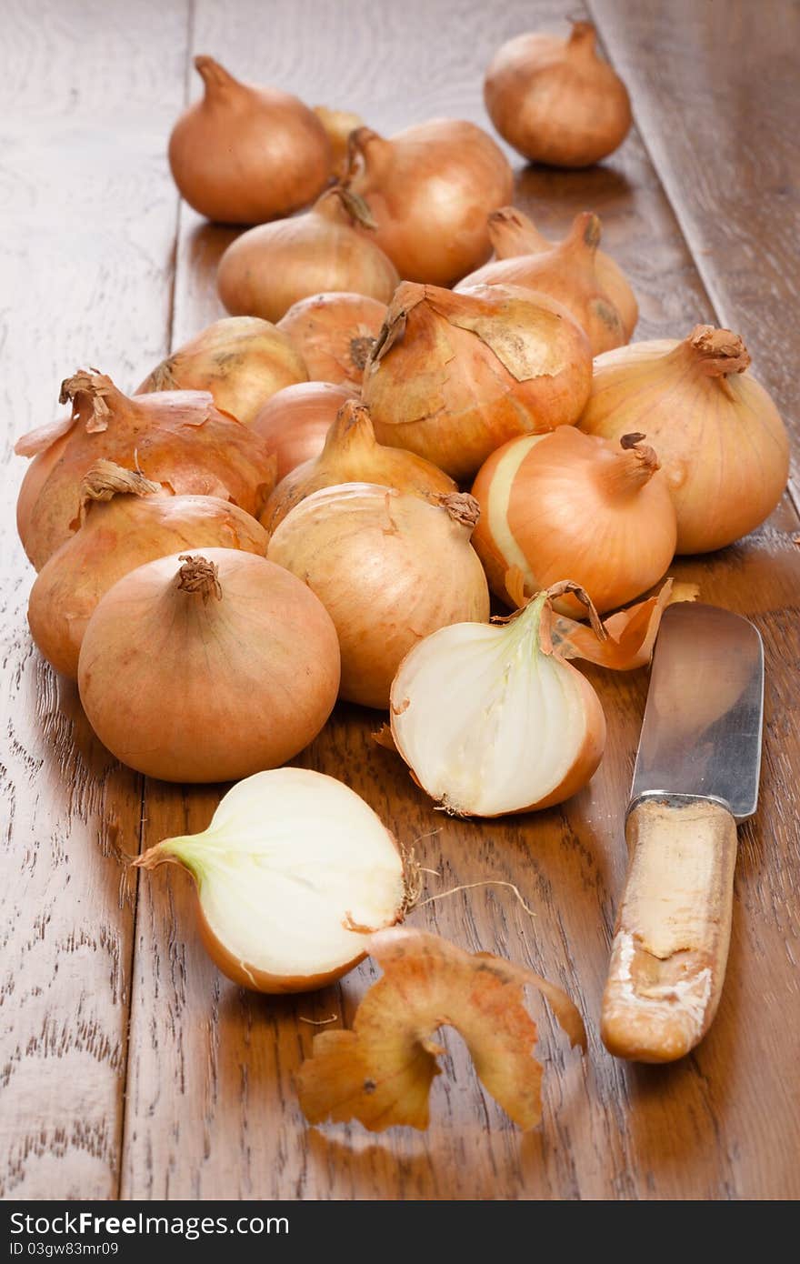 Small onions on a wooden table one half cut with a knife