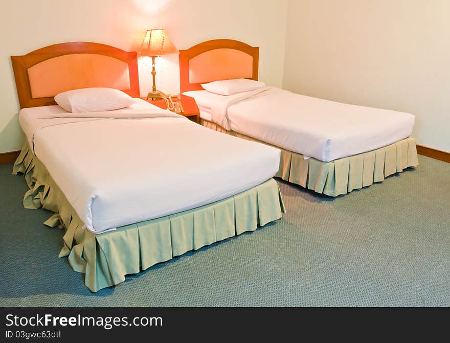 Twin generic white bed with lamp between them. Twin generic white bed with lamp between them