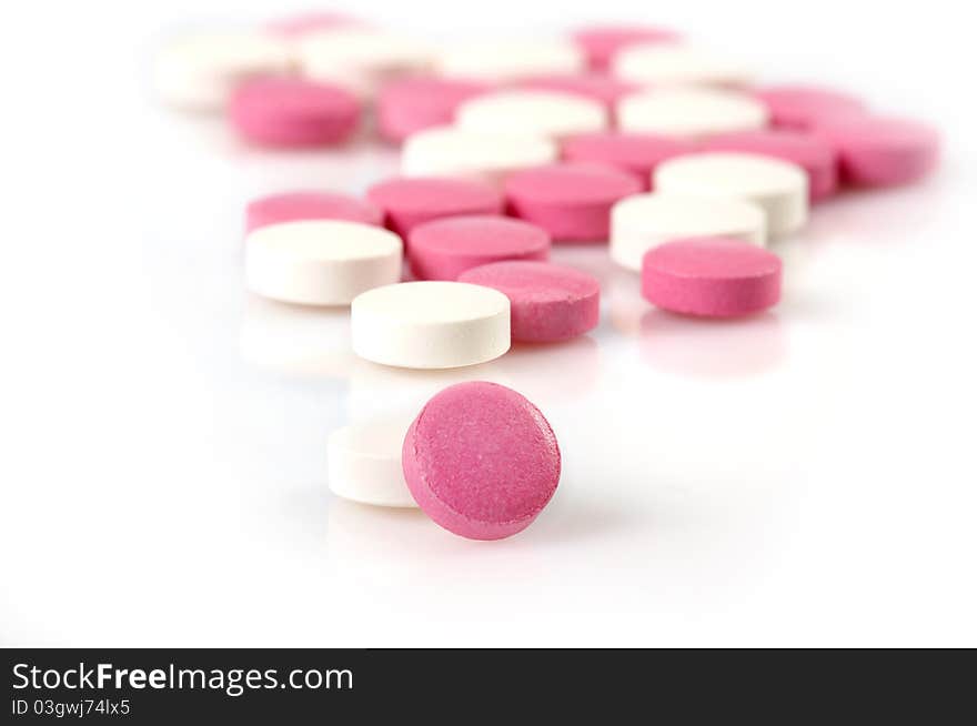 White and pink pills on white background