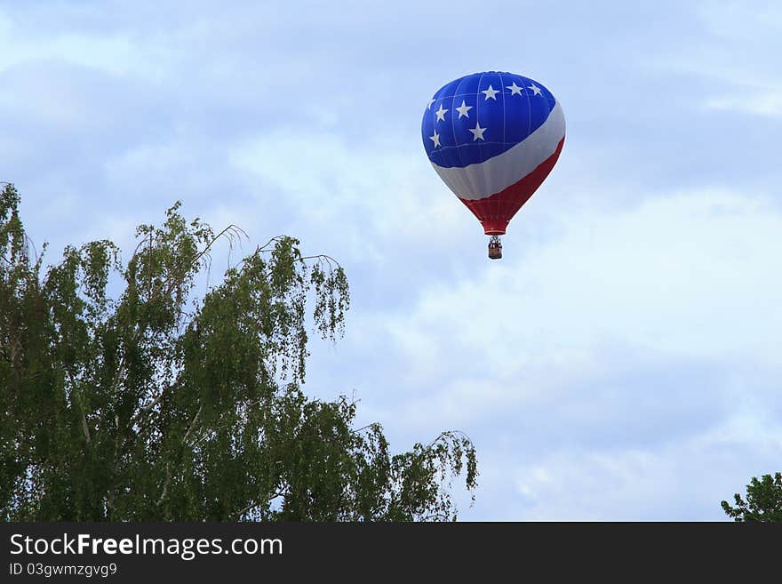 Red, White and Blue hot air balloon taking off over eastern washington and flying over trees. Red, White and Blue hot air balloon taking off over eastern washington and flying over trees