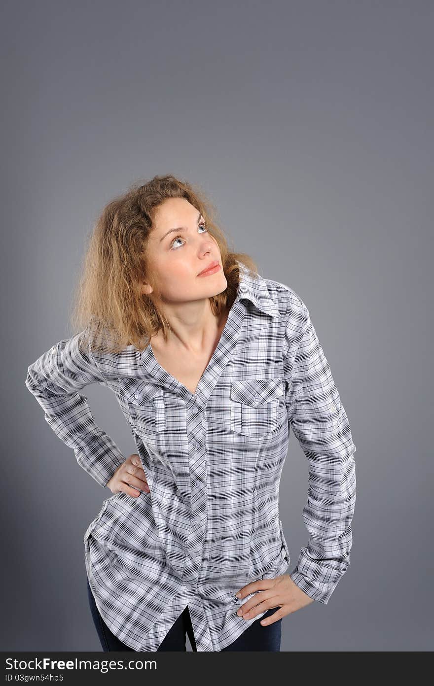 Portrait of a surprised woman looking upwards at copyspace against grey background. Portrait of a surprised woman looking upwards at copyspace against grey background