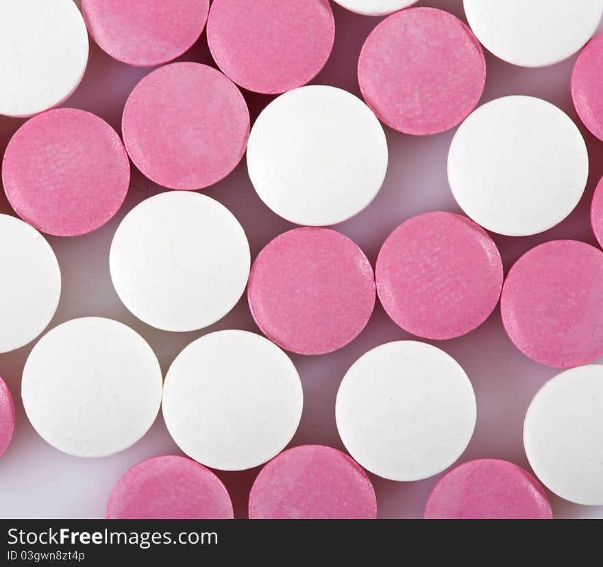 Pink and white pills on white background