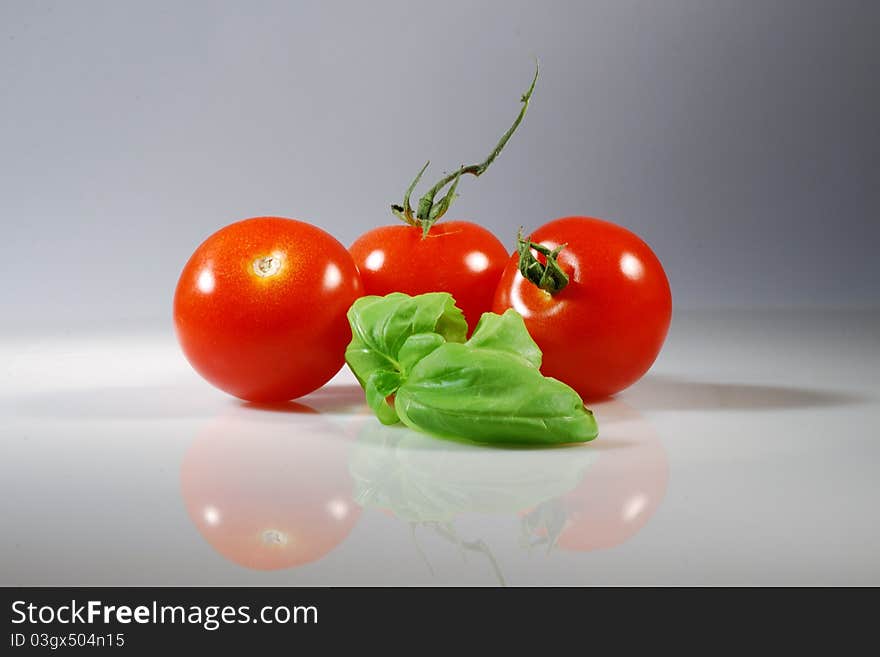 Three red tomato with a basil leaf. Three red tomato with a basil leaf