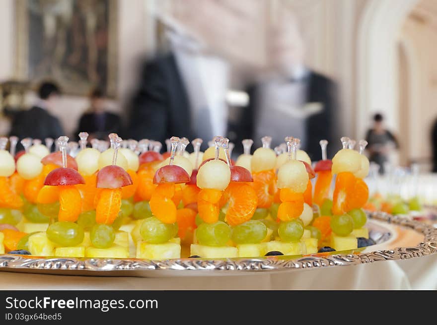 Fruit snack on a tray against the background of unrecognizable people. Background slightly desaturated for the highlighting of foreground. Fruit snack on a tray against the background of unrecognizable people. Background slightly desaturated for the highlighting of foreground.