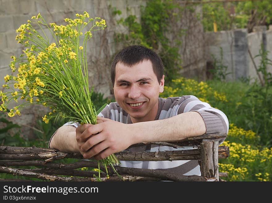 A young man awaits his girlfriend with a bouquet of yellow flowers