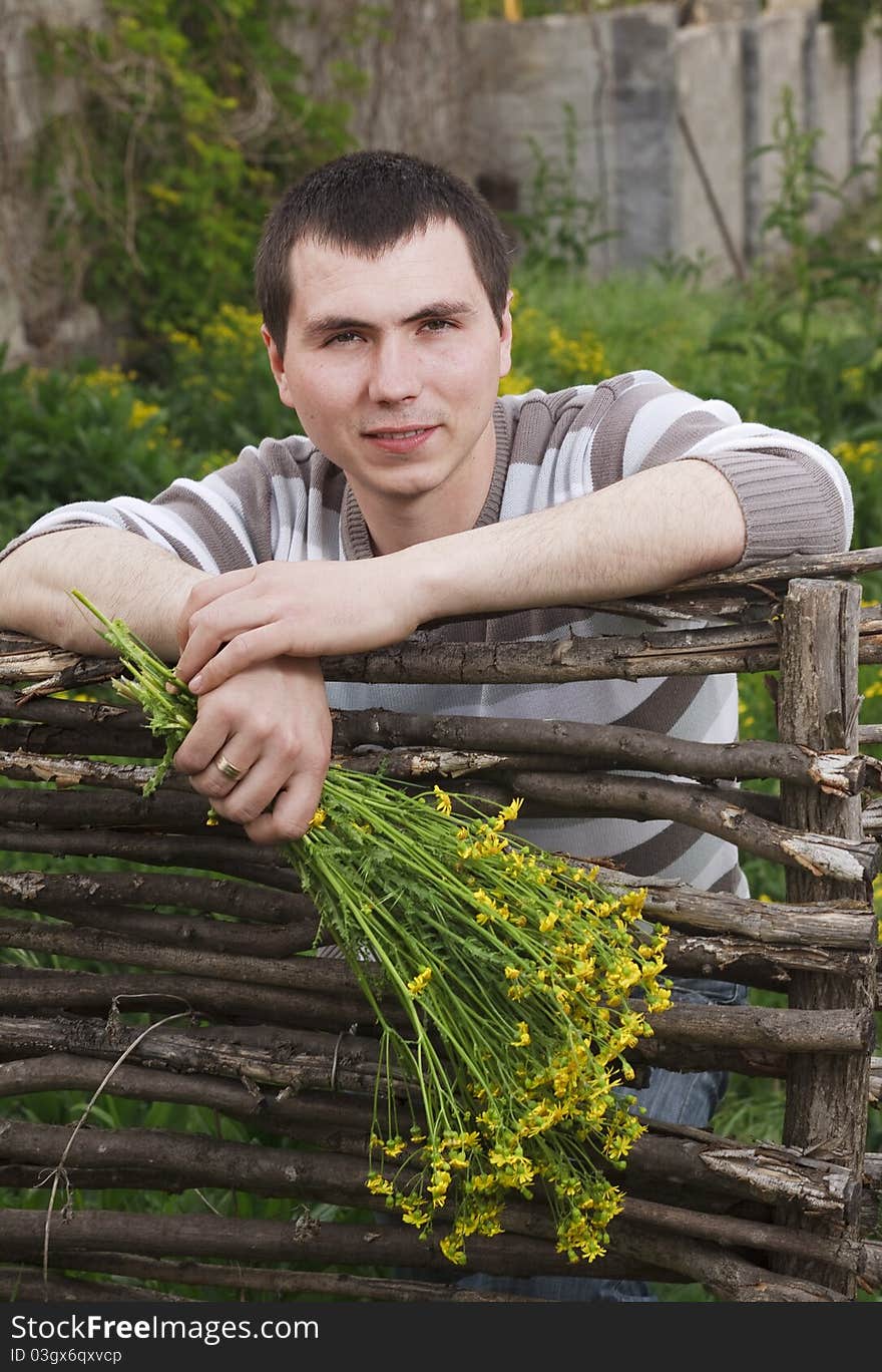 A young man awaits his girlfriend with a bouquet of yellow flowers