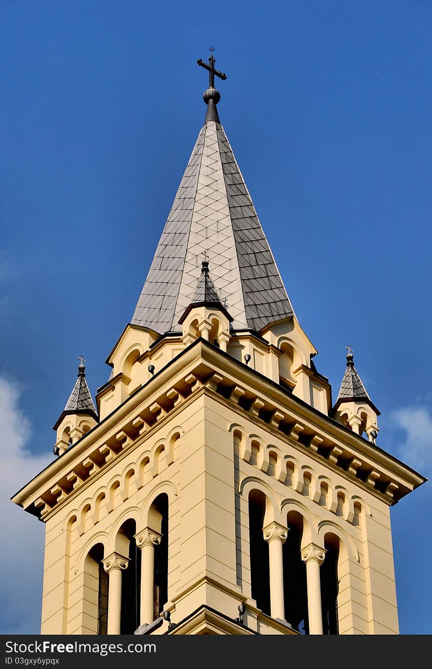 A cross on top of a church against blue sky with a few clouds - copy space. A cross on top of a church against blue sky with a few clouds - copy space