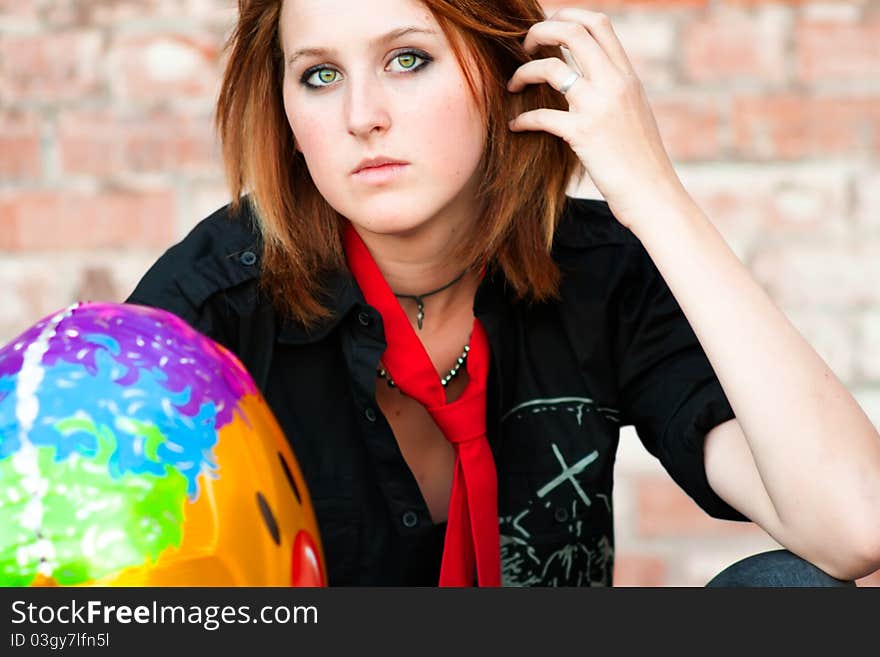 A portrait of a serious looking young woman holding a smiley face balloon. A portrait of a serious looking young woman holding a smiley face balloon