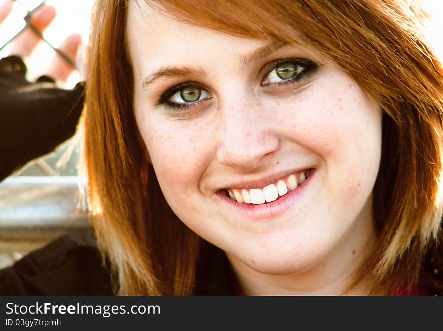 A portrait of a happy looking young woman leaning against a fence. A portrait of a happy looking young woman leaning against a fence