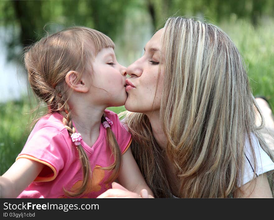 Little Girl Kissing Her Mother In  Park