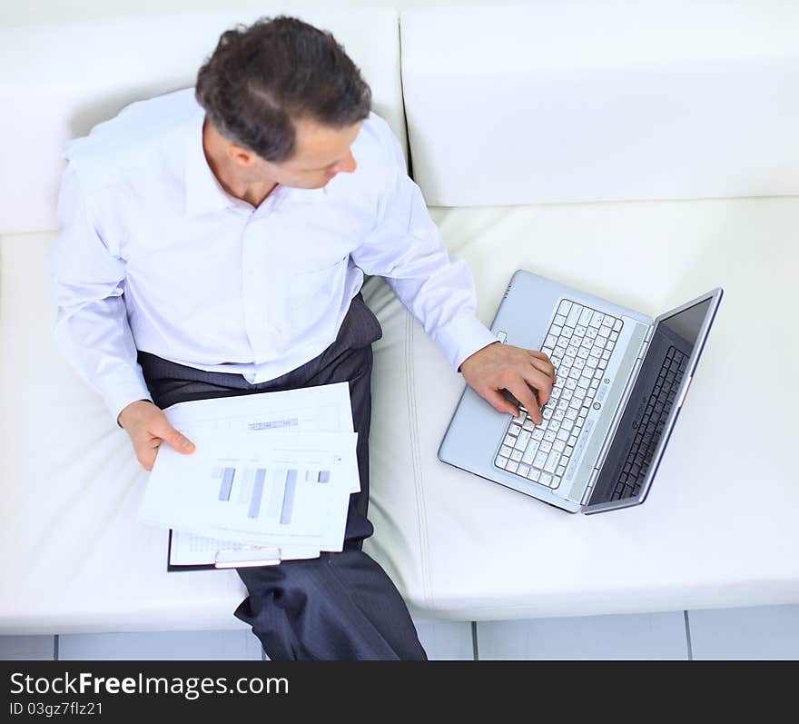 Senior businessman sitting on sofa and using laptop