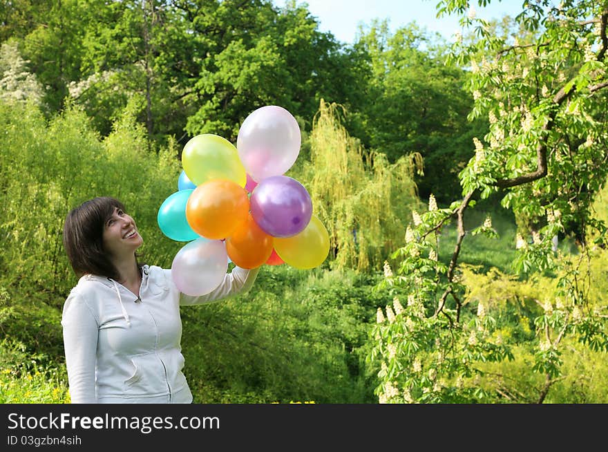 Holiday.Woman with color balloons against a blossoming trees. Holiday.Woman with color balloons against a blossoming trees