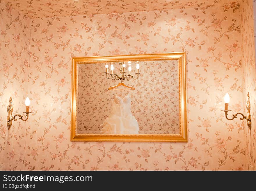 White wedding dress is reflecting in the mirror on the wall. White wedding dress is reflecting in the mirror on the wall