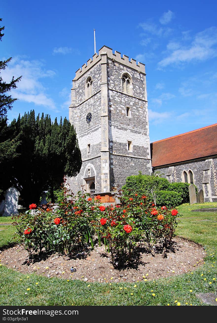 English Village Church and Tower with a flowerbed of Red Roses in the foreground. English Village Church and Tower with a flowerbed of Red Roses in the foreground