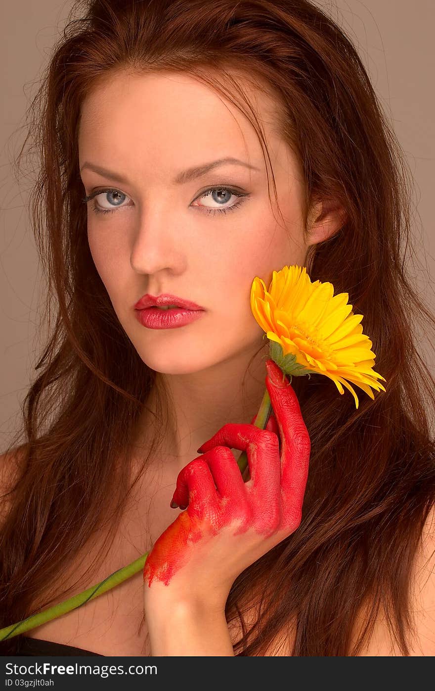 A portrait of a pretty female painter holding a yellow gerbera in her hand. A portrait of a pretty female painter holding a yellow gerbera in her hand.