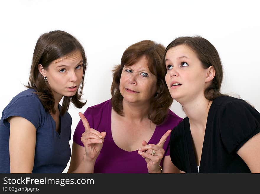 Mother pointing fingers at her daughters with silly expression. Mother pointing fingers at her daughters with silly expression.