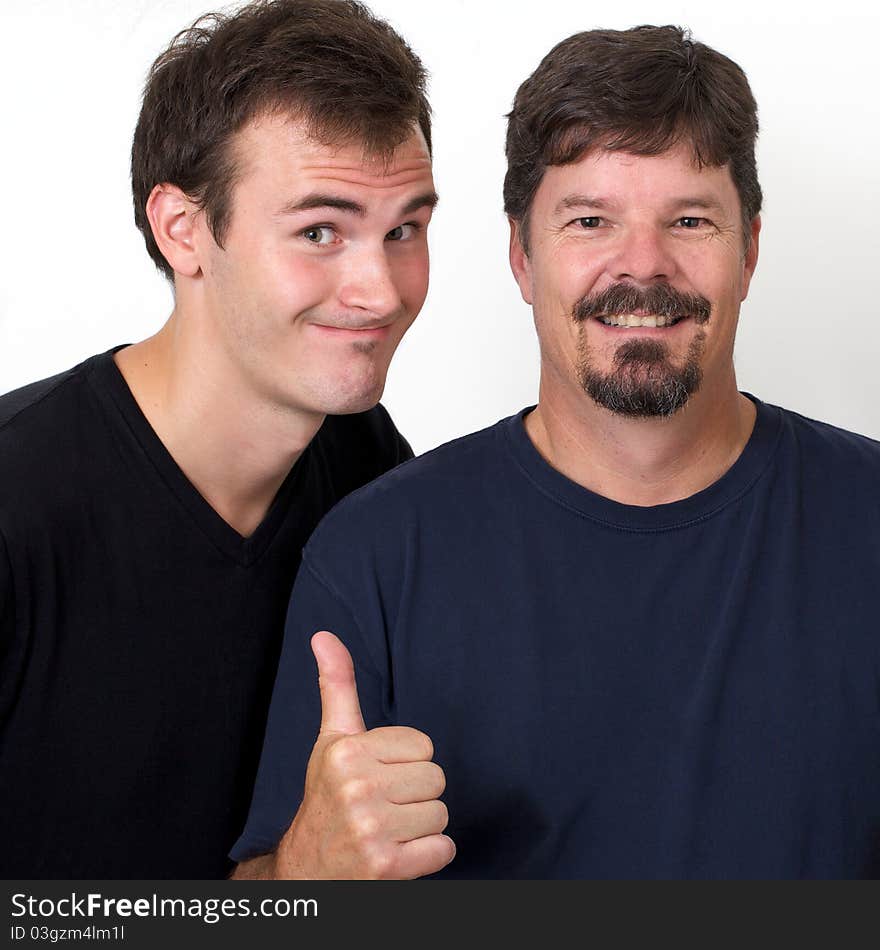 Mature man shows his approval for younger man with a proud thumbs up and a smile on his face. The young man therefore smiles back in appreciation. Mature man shows his approval for younger man with a proud thumbs up and a smile on his face. The young man therefore smiles back in appreciation.