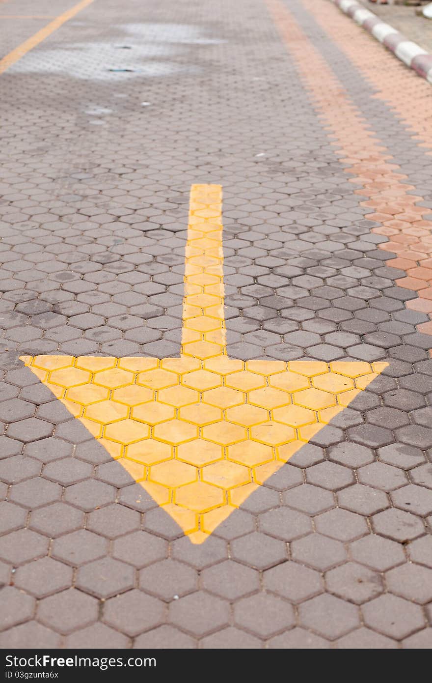 Yellow arrow on the ground, arrow near sidewalk in tha park