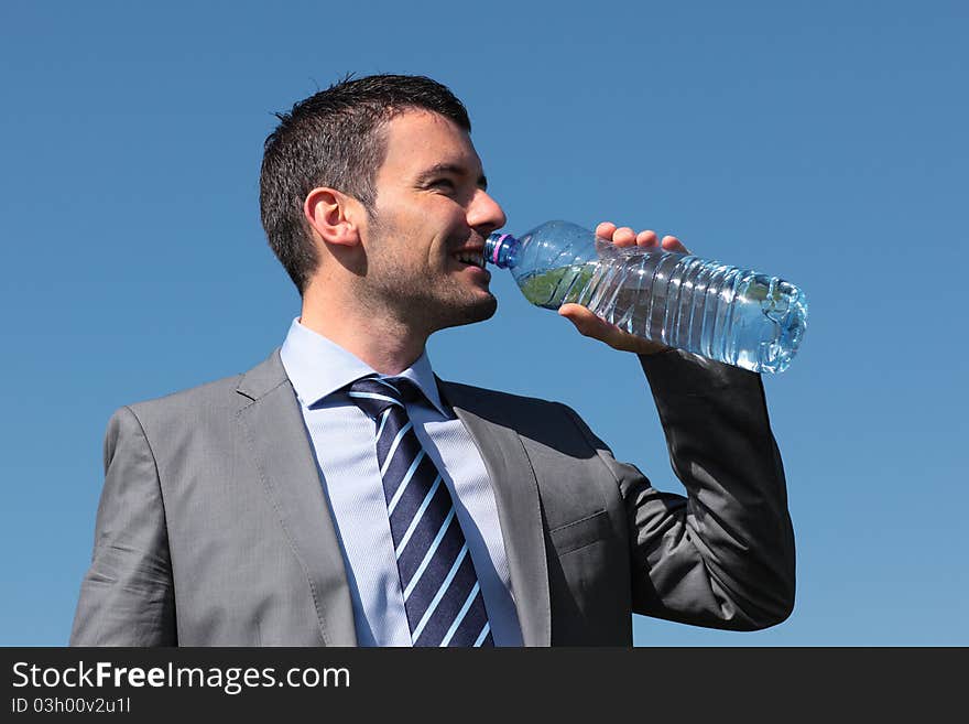 Businessman drinking water with bottle and blue sky