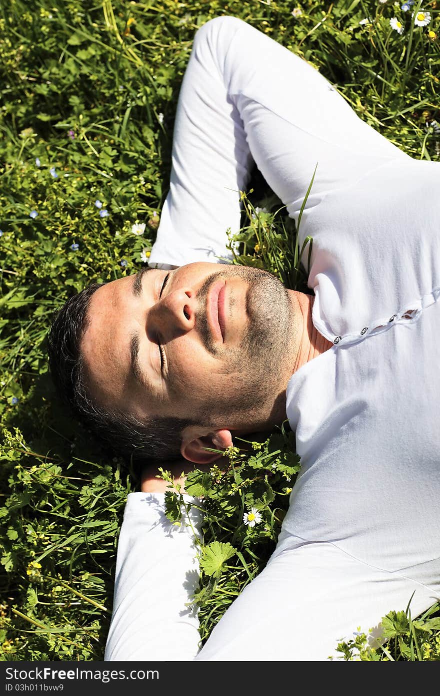 Young man sleeping on the grass in summer