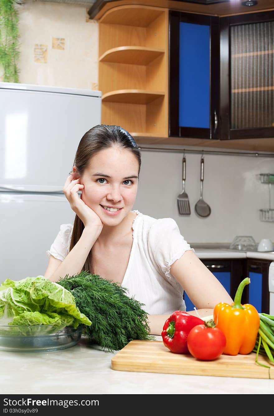 Young beautiful caucasian woman in the kitchen with vegetable