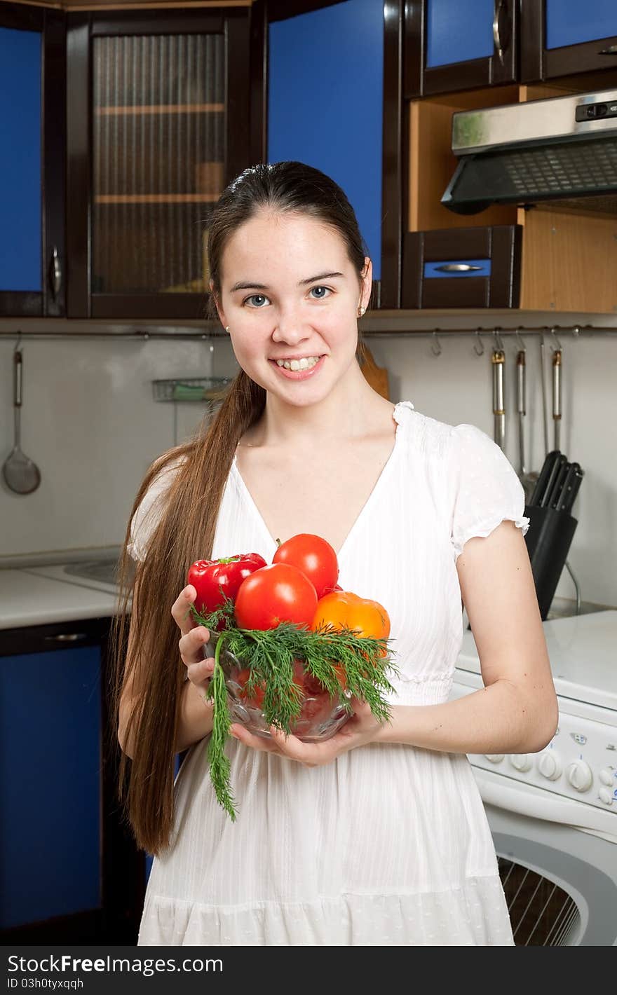 Young beautiful caucasian woman in the kitchen with vegetable