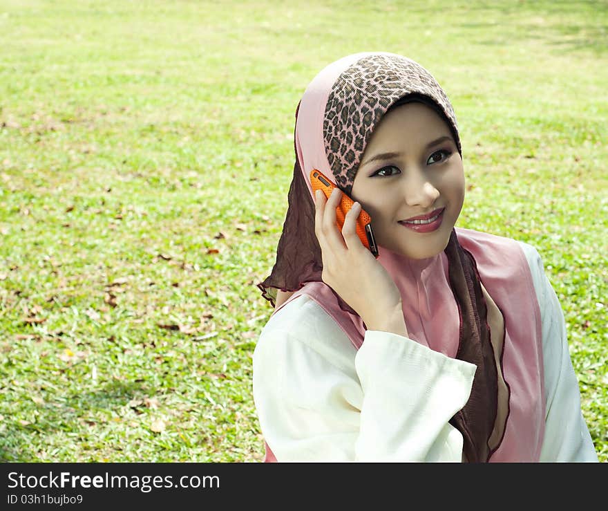 Pretty Muslim girl with a phone at garden