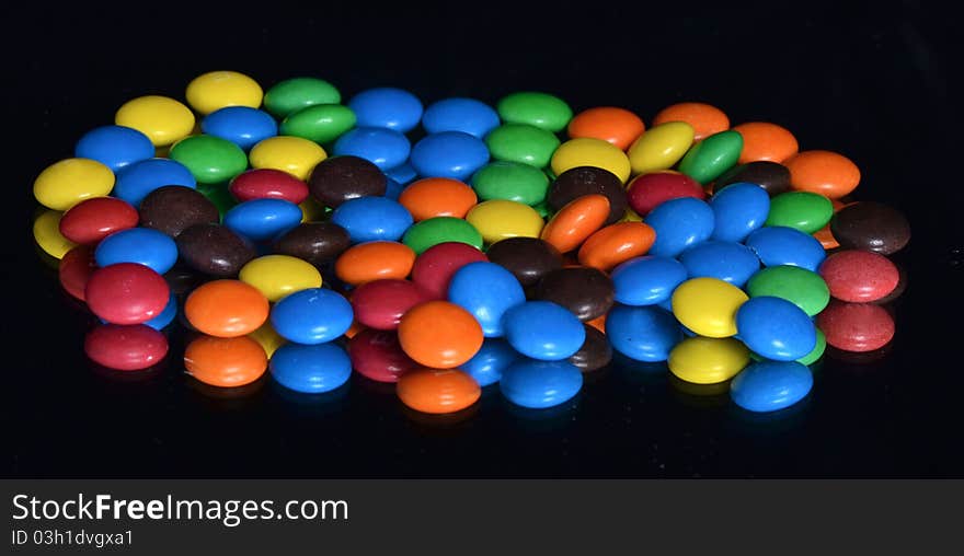 Chocolate glazed multicolored dragee on the black background. Chocolate glazed multicolored dragee on the black background