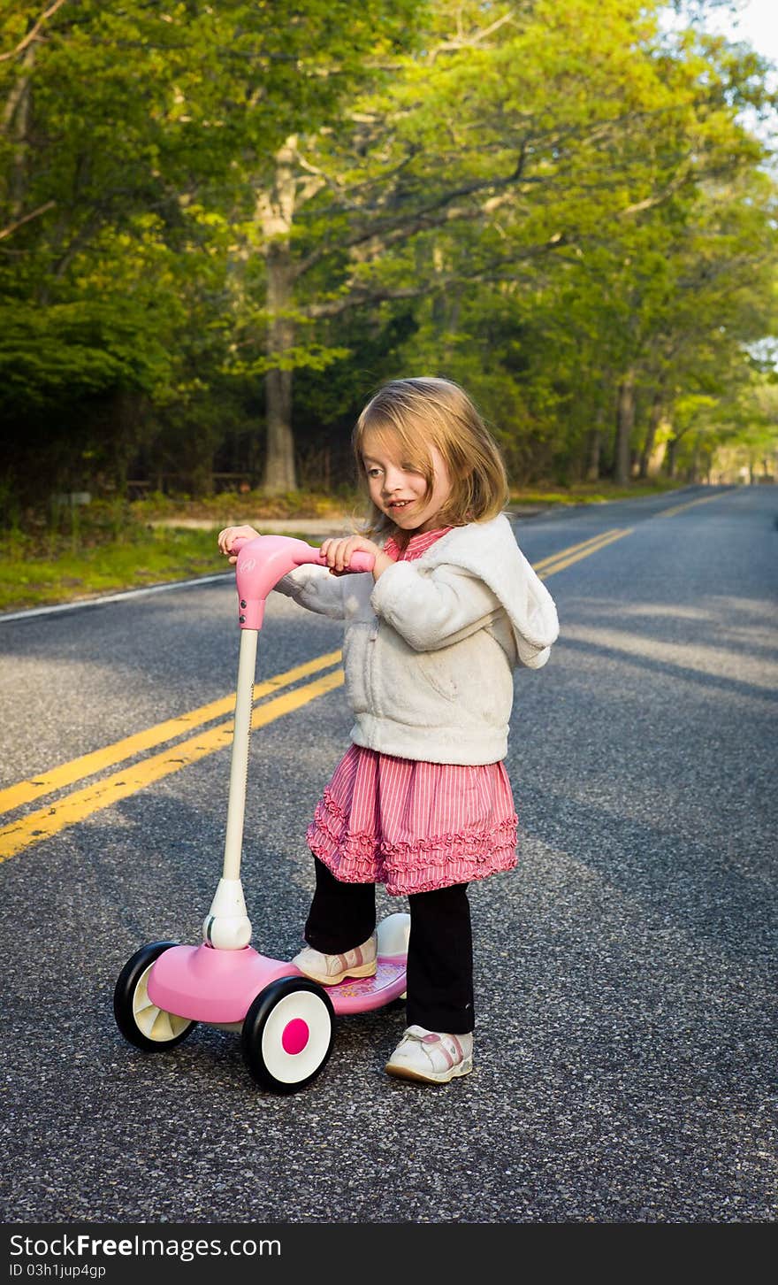 Little Girl Riding a Pink Scooter