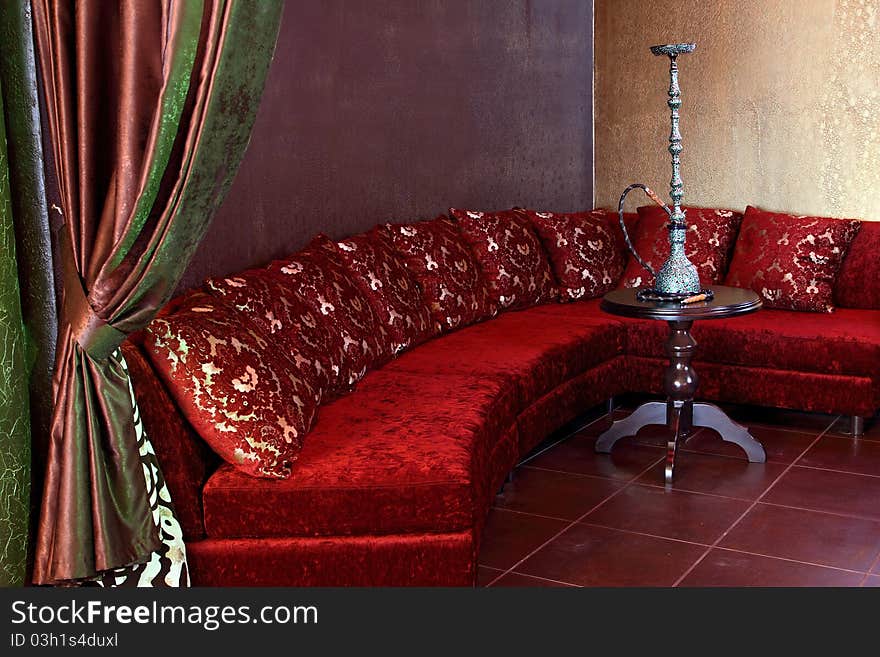 Room with a sofa, with pillows and a little table with a beautiful hookah.