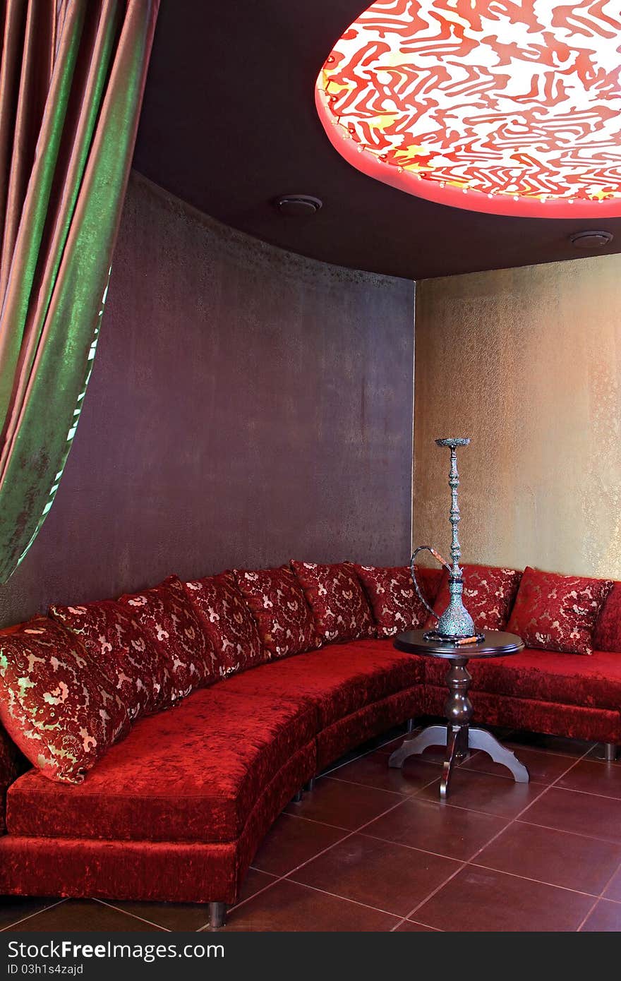 Room with a sofa, with pillows and a little table with a beautiful hookah.