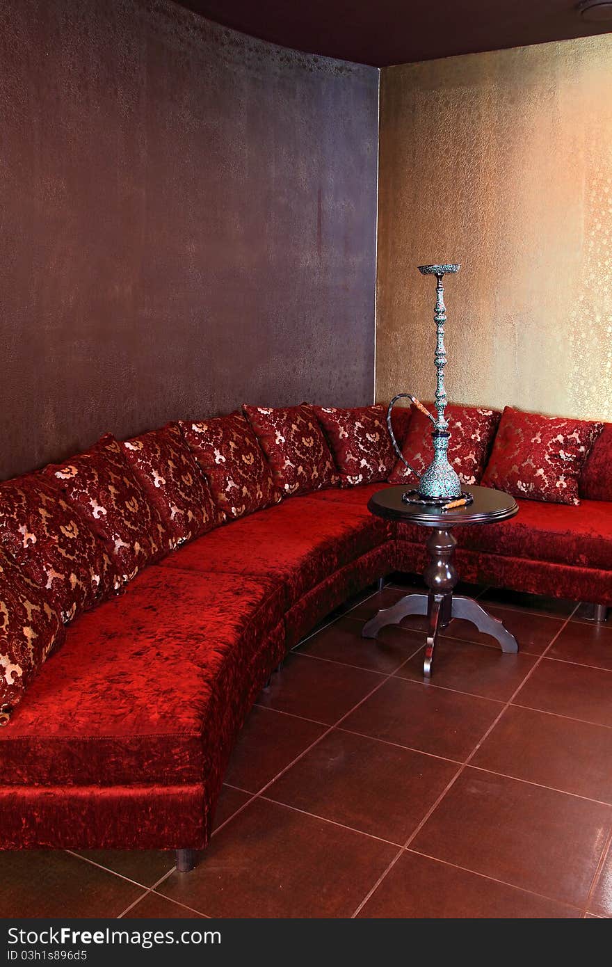 Room with a sofa, with pillows and a little table with a beautiful hookah.