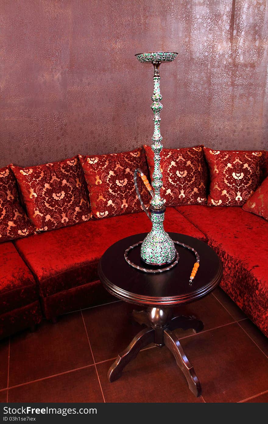 Room with a sofa, with pillows and a little table with a beautiful hookah.