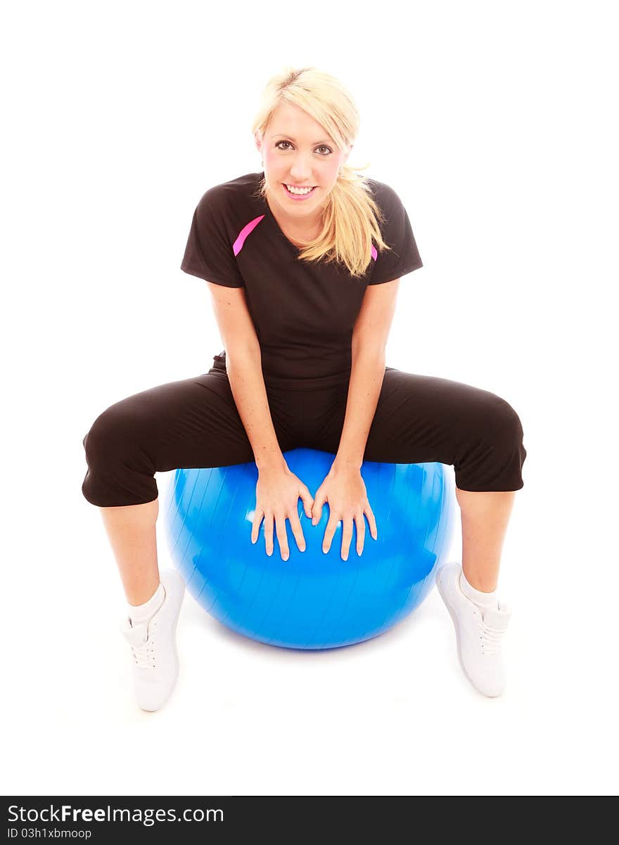 A young female dressed in gym clothes sat on a blue gym ball on isolated white background. A young female dressed in gym clothes sat on a blue gym ball on isolated white background