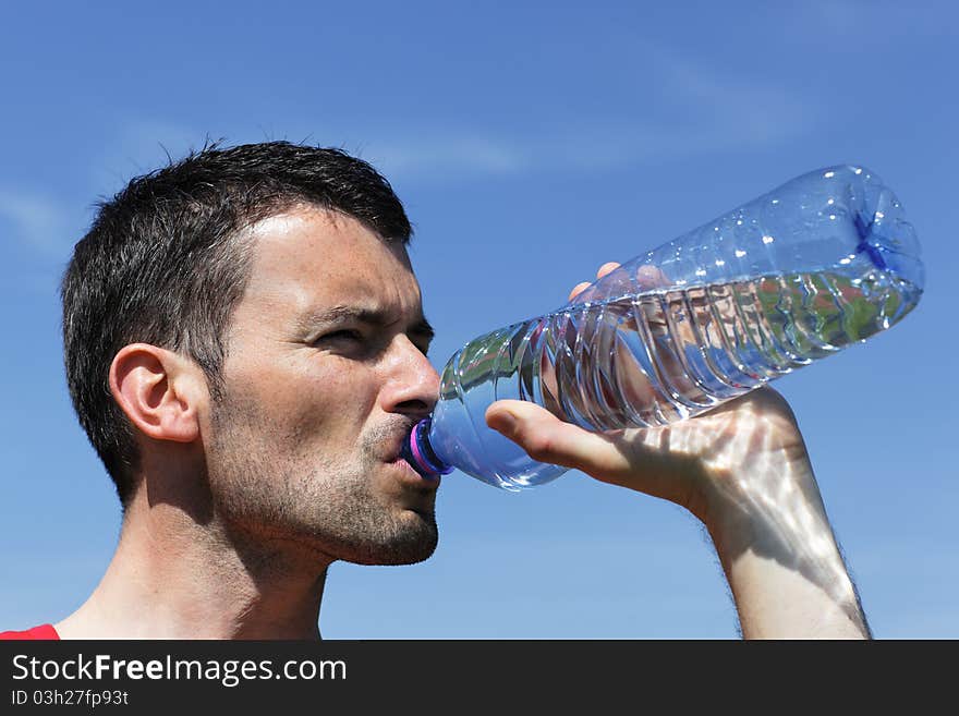 Young man drinking water in blue sky