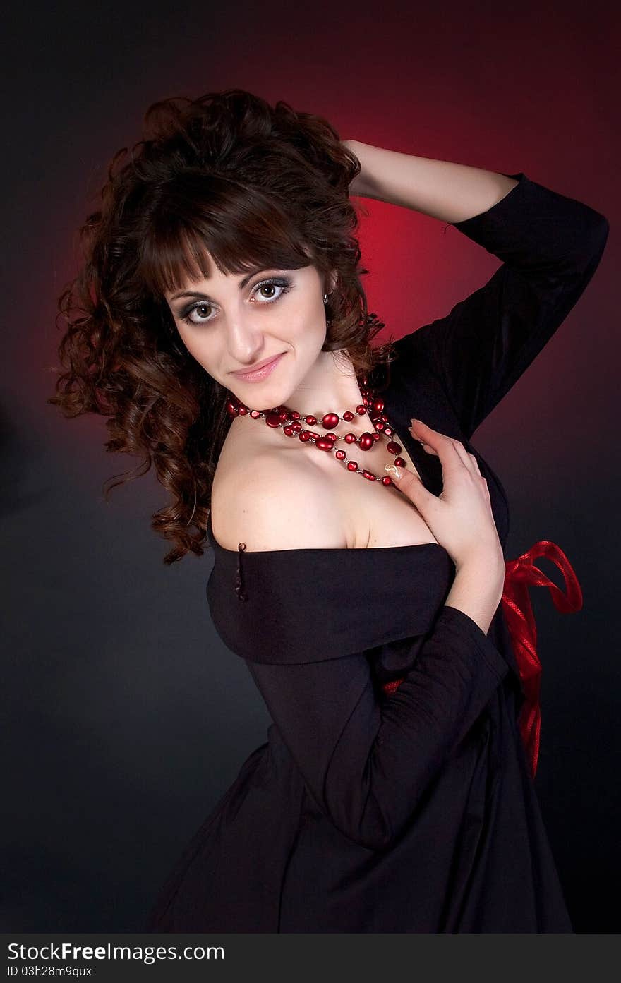 Cute brunette in red beads on a dark background