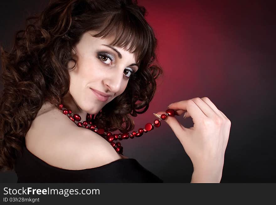 Cute brunette in red beads on a dark background