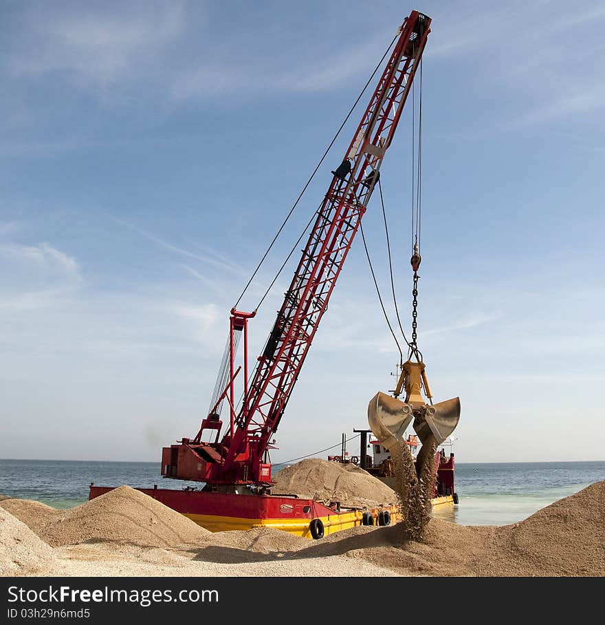 Bucket is downloading sand over the beach. Bucket is downloading sand over the beach