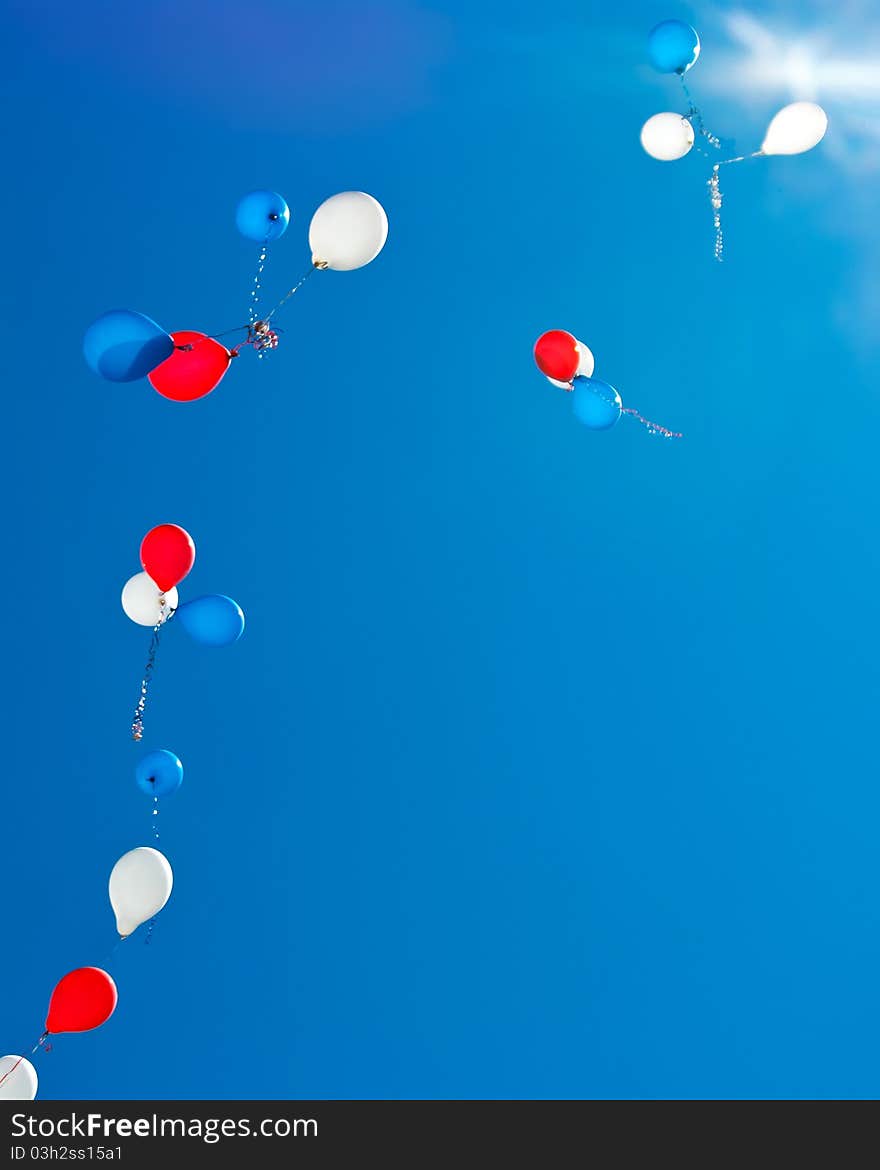 Colorful balloons, flying toward the sun against the blue sky